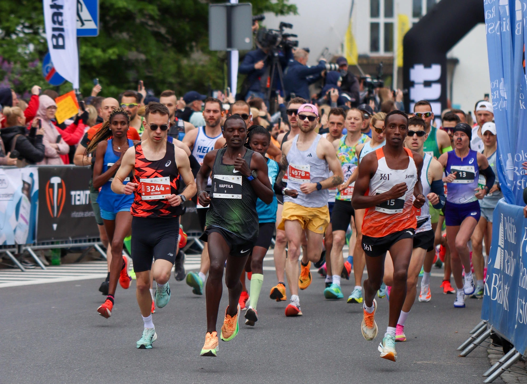 Zawodnicy ruszający ulicą pomiędzy kibicami i banerami półmaratonu