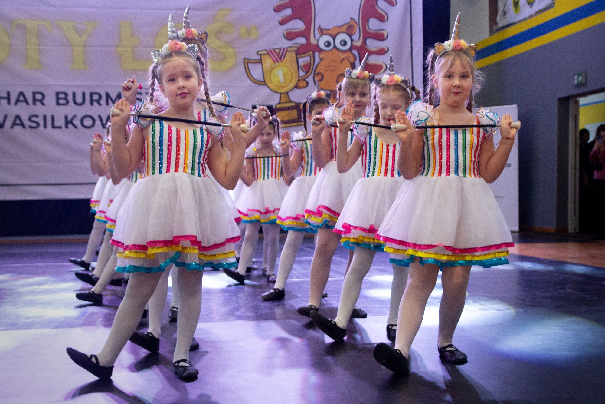 Zespół w białych sukienkach z kolorowymi pasami podczas wspólnego występu