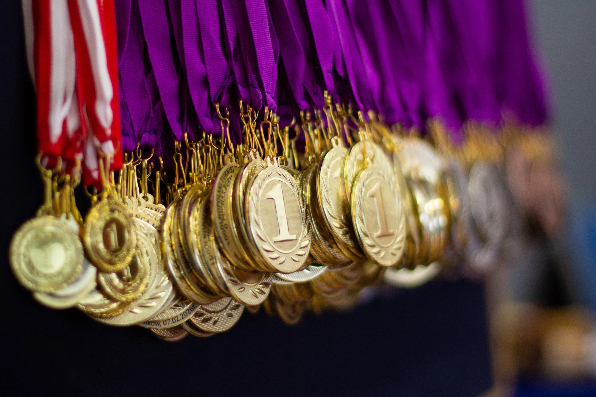 Zbliżenie złotych medali na fioletowych i biało-czerwonych wstążkach